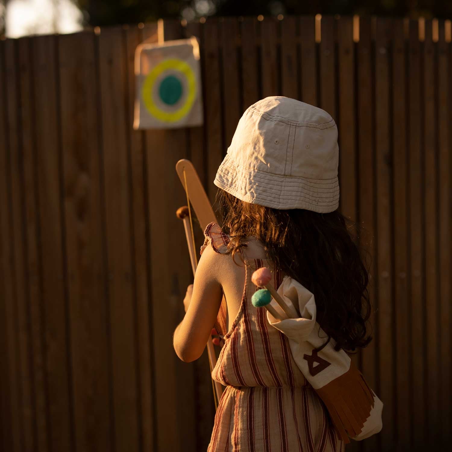 back of girl playing bow and arrow toys