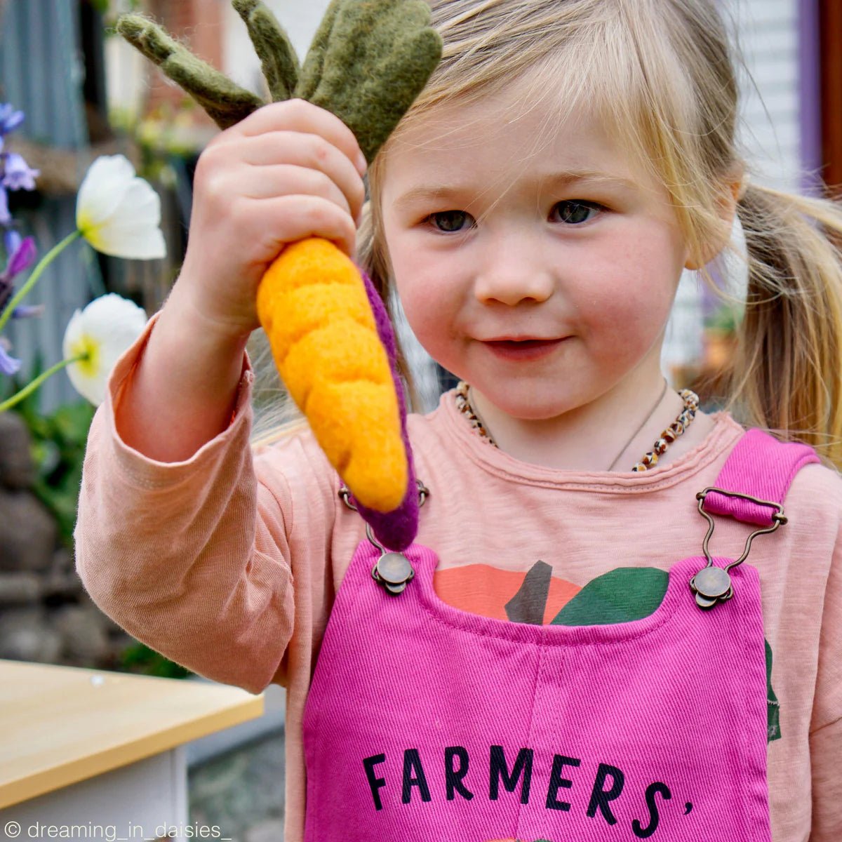 Girl holding felt play food carrot