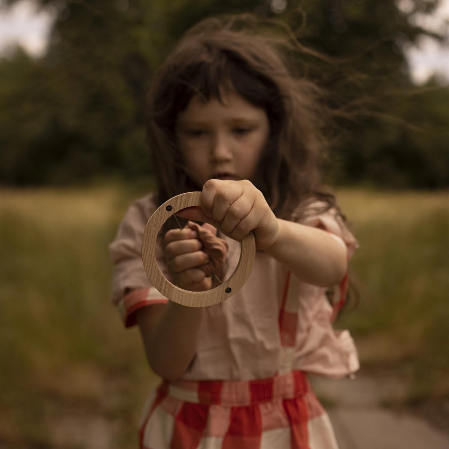 girl playing with wooden slingshot toy