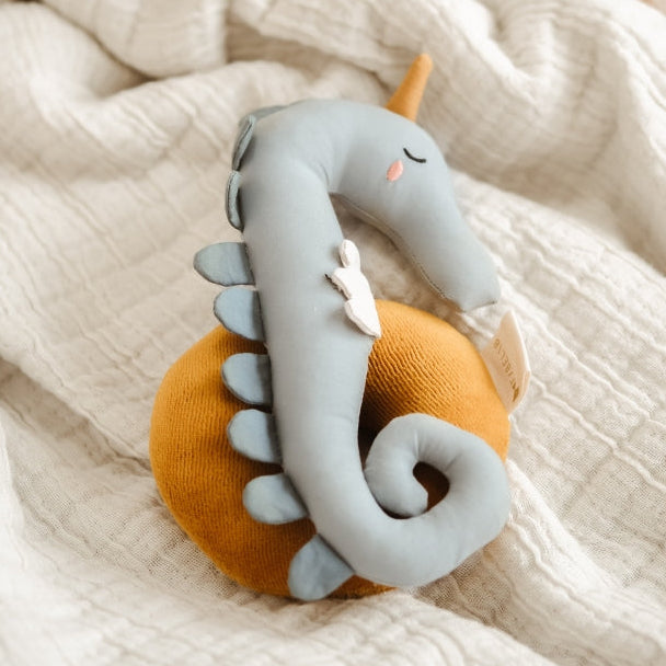 Organic cotton plush toy seahorse baby rattle on a textured blanket