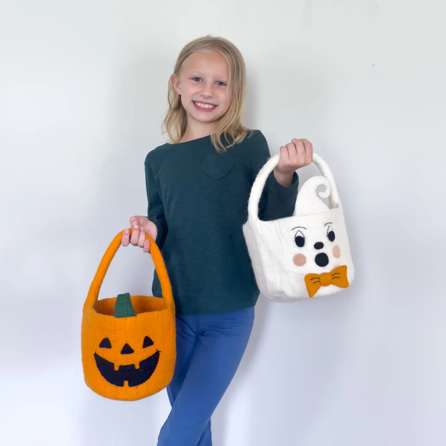 girl holding handmade felt halloween pumpkin and ghost trick or treat baskets