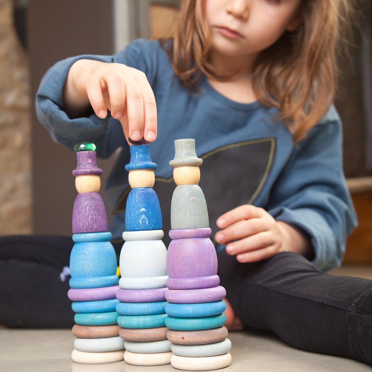 child playing with grapat aguamarina winter nins play set with peg dolls, mates, coins, and rings in blues and violets.