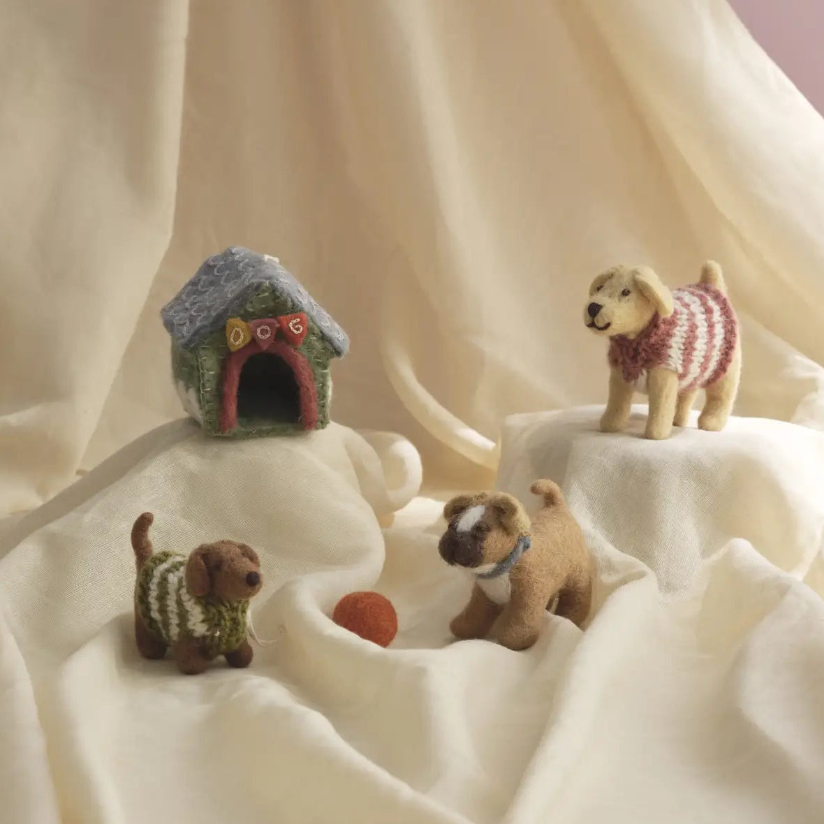 Three small felt miniature toy dogs with a small doghouse nearby.
