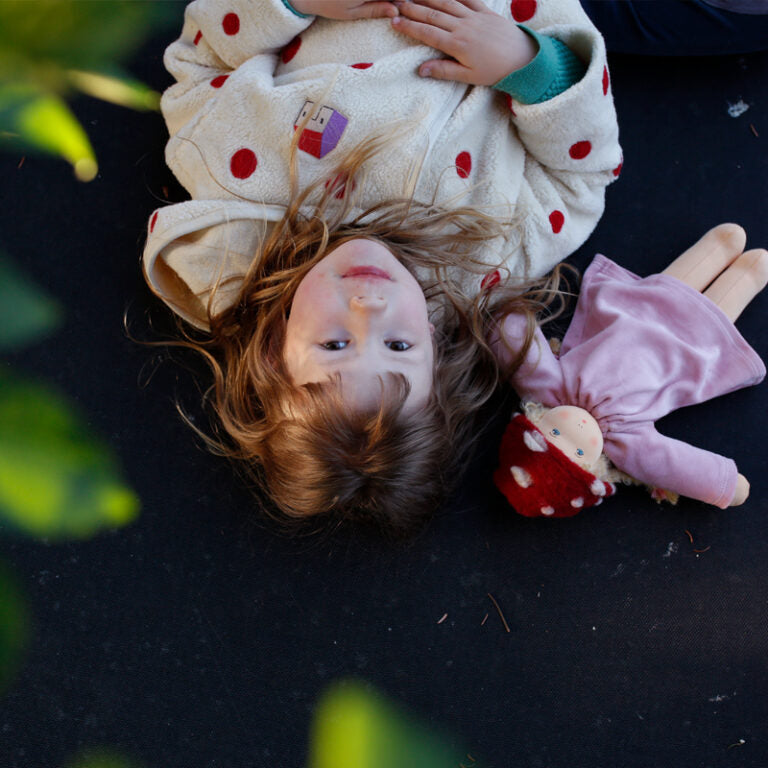 girl lying next to nanchen waldorf doll garden child lolle with mushroom cap