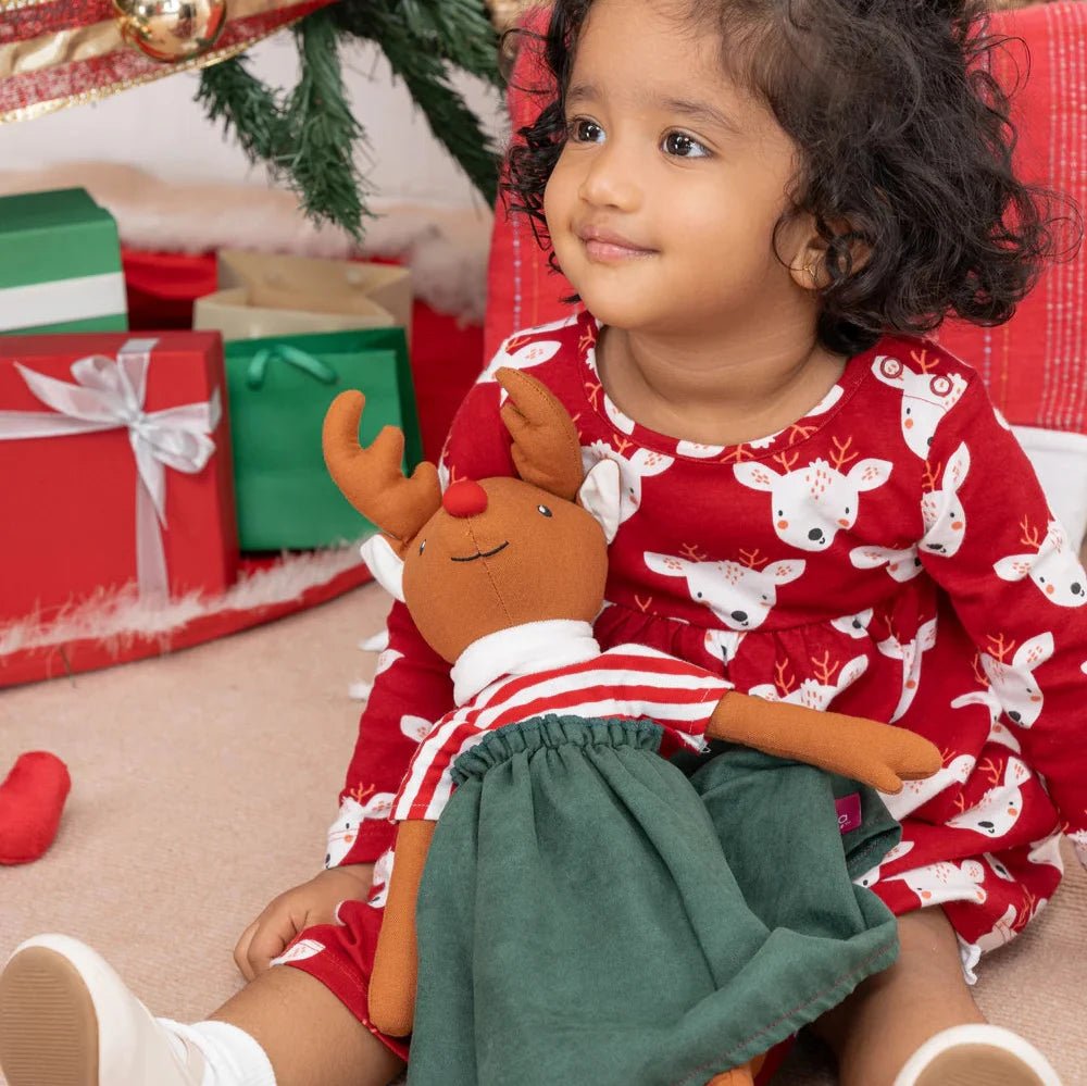 girl with stuffed animal reindeer in skirt and top on Christmas