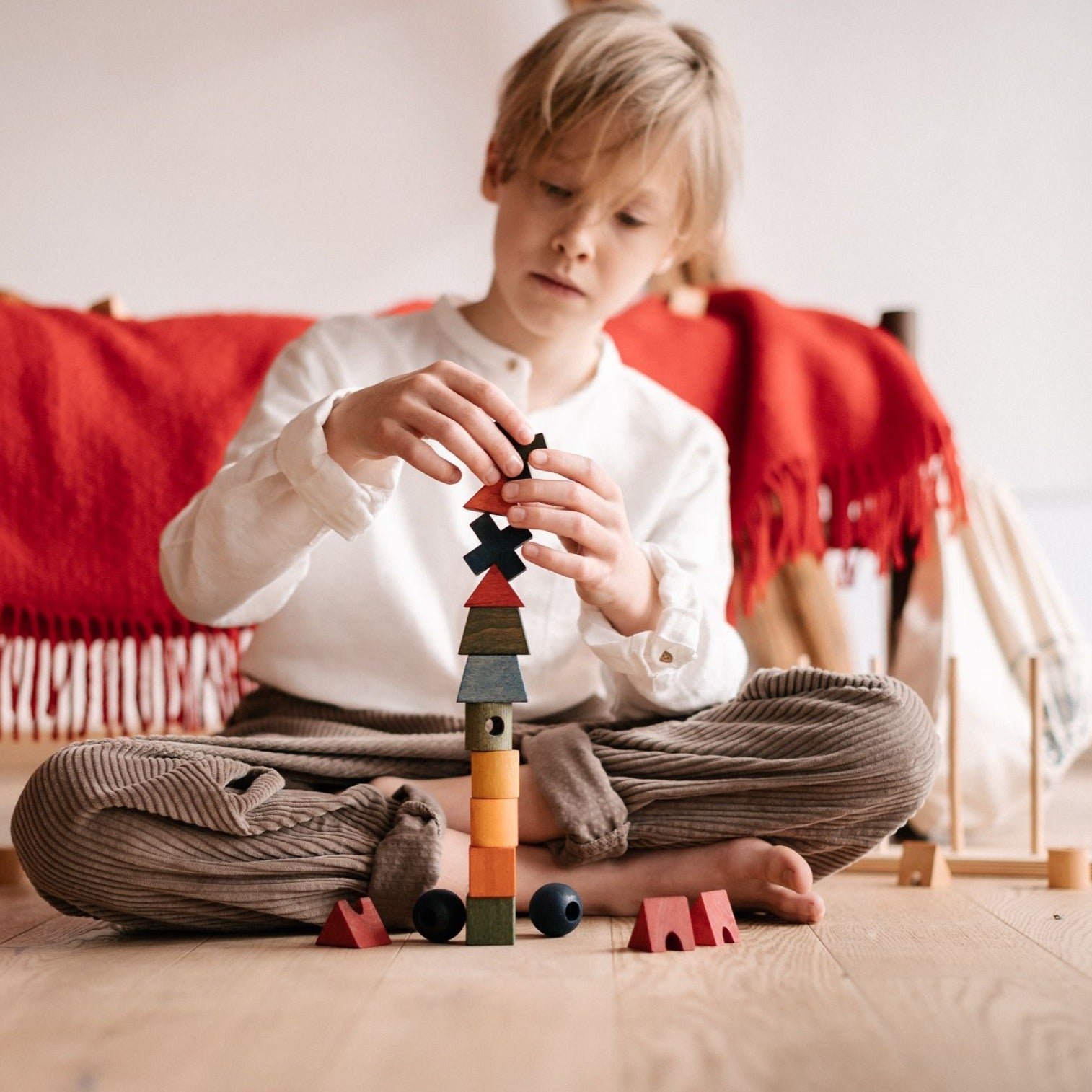 boy stacking wooden rainbow shapes