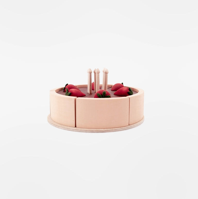 A wooden toy cake in a light wood with chocolate layers, decorated with red strawberries and four small wooden candles.