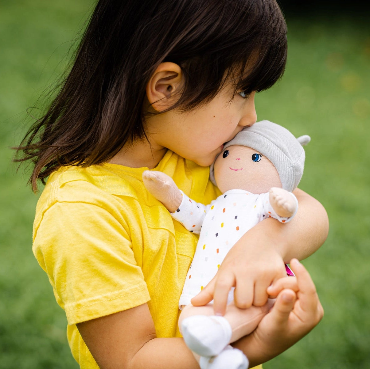 girl kissing her tikiri toys bonikka gender neutral cotton baby doll