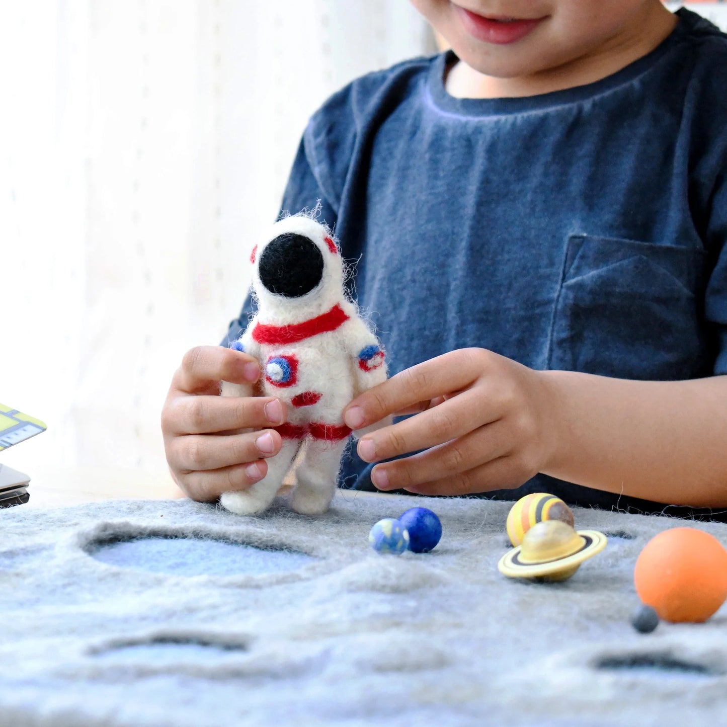 Boy playing with Tara Treasures felt astronaut figure