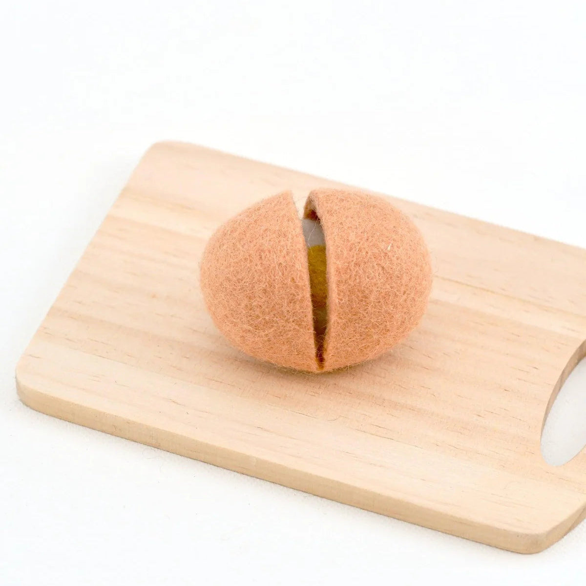 Half-cracked felt play food eggshell with an egg inside on a wooden cutting board