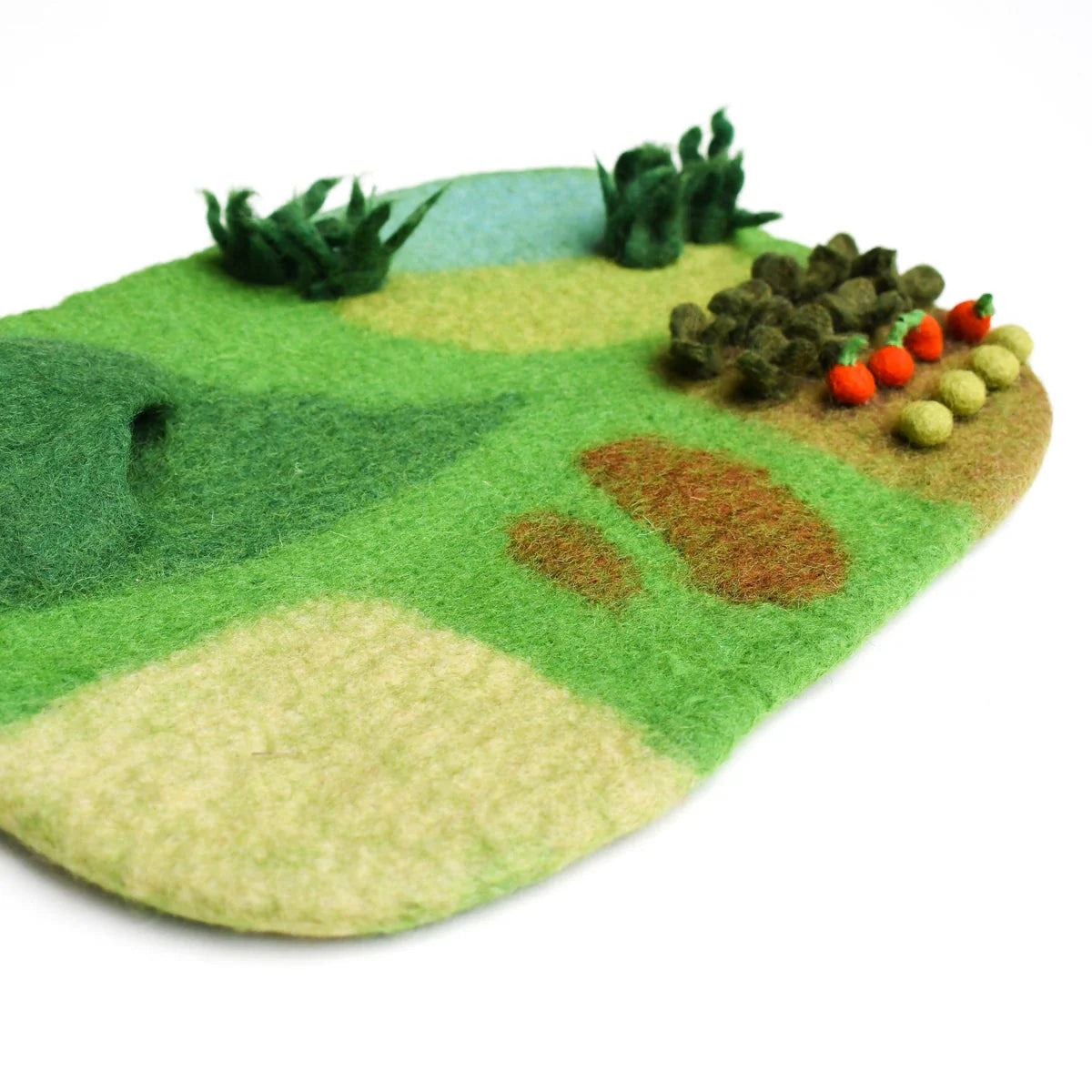 Felt farm play mat with green grass, brown dirt, a cave, and colorful vegetables