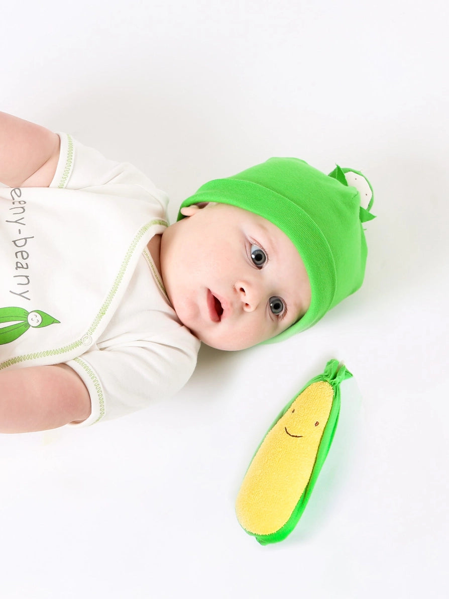 Baby next to an organic plush corn veggie toy.