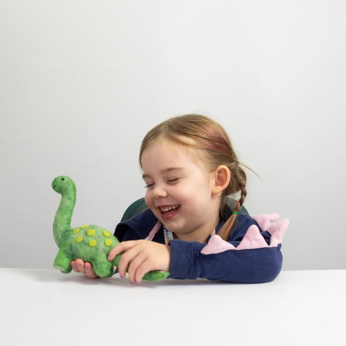 girl playing with winding road had felted dinosaur toy