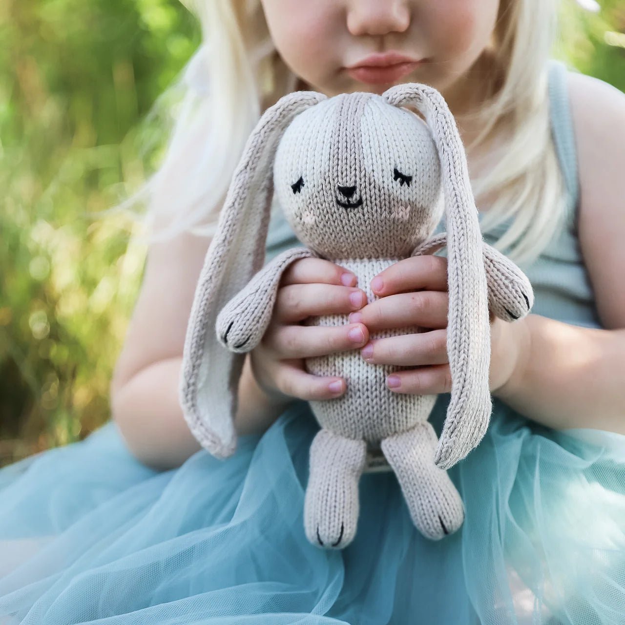 girl holding red and olive bunny rabbit doll