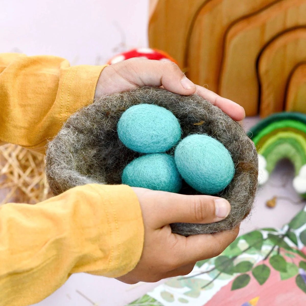 Child holding felted toy bird nest and eggs