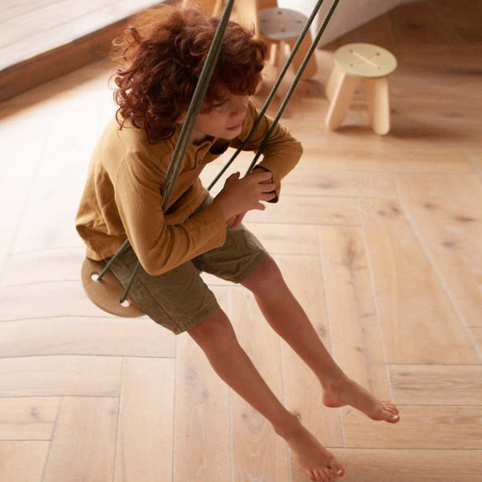 boy on wooden swing with khaki rope