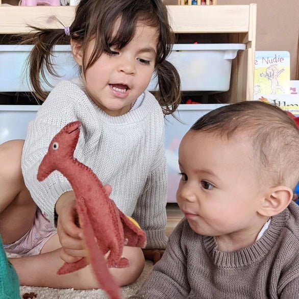 girl and boy playing with pteranodon stufffed animal