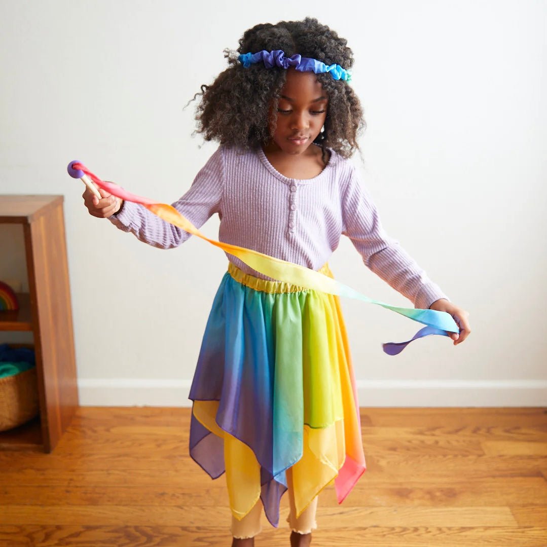 Girl dressed like a fairy playing with Sarah's silks mini rainbow streamer wand