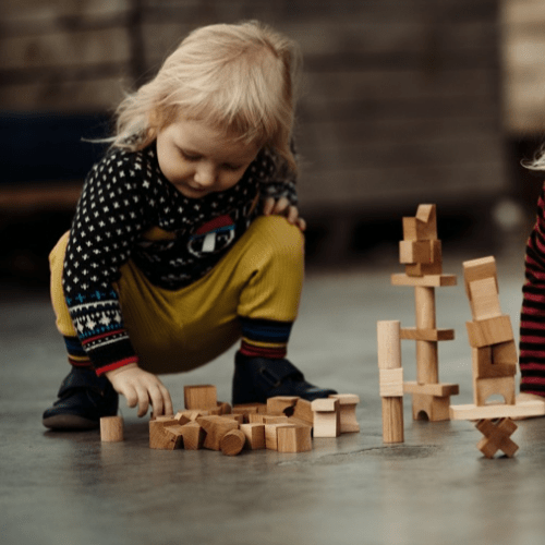 girl playing with natural wood stacking blocks