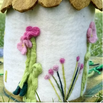 Felted fairy cottage house with floral details on a grassy playmat
