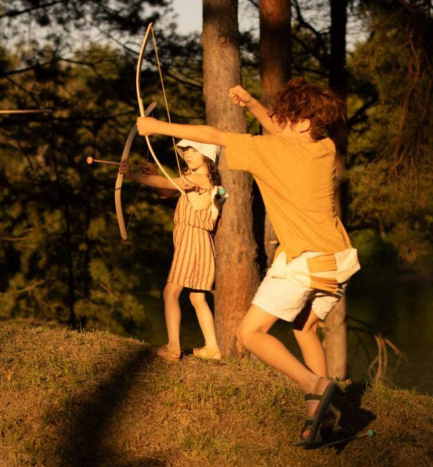 kids playing with wooden bow and arrow set in nature