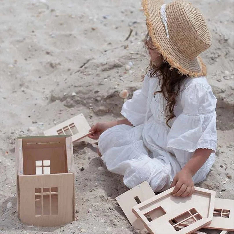 Girl building a Babai magnetic wooden dollhouse in the sand