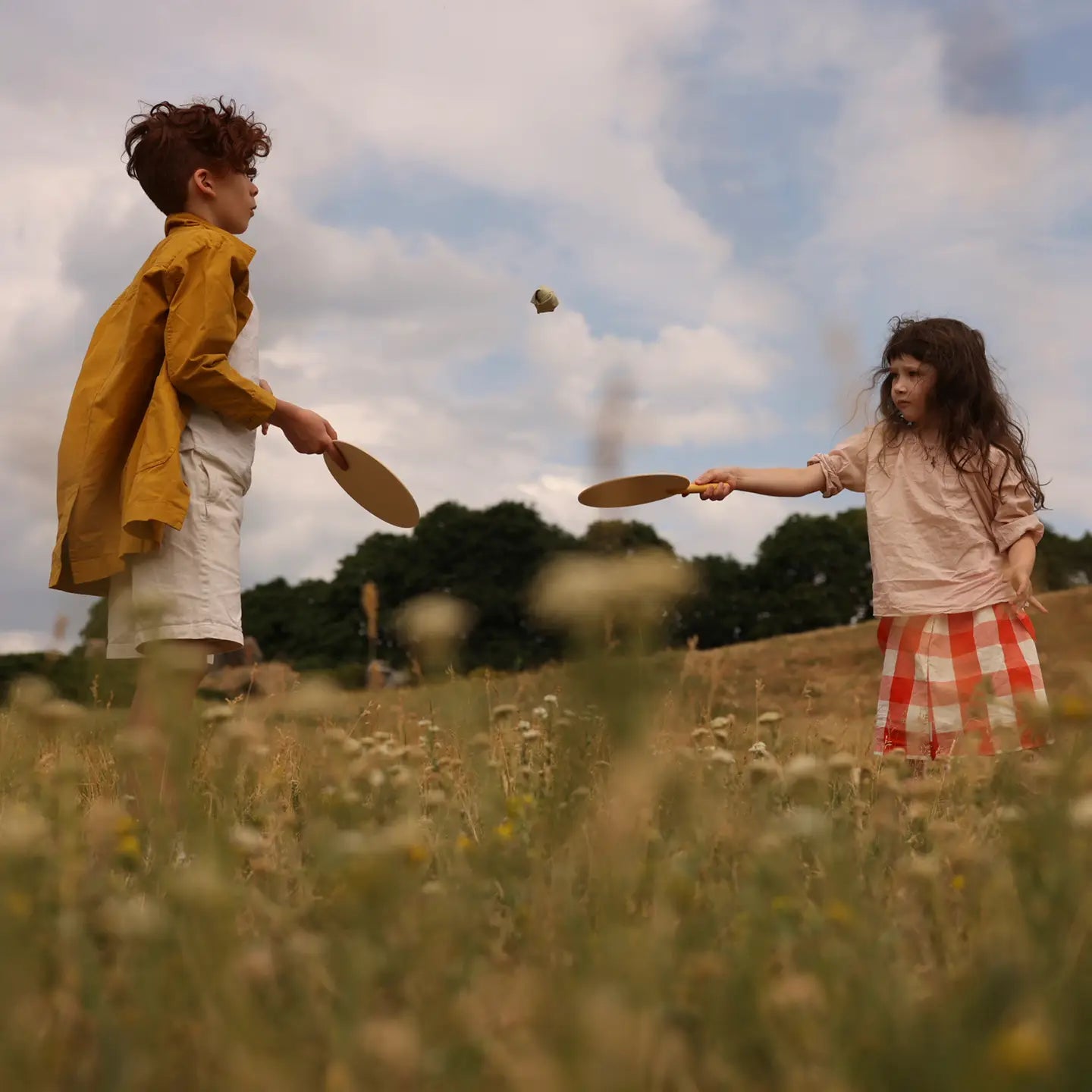 kids playing badminton with wooden paddles and soft balls