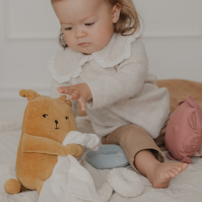 Child playing with a soft organic teddy bear music box