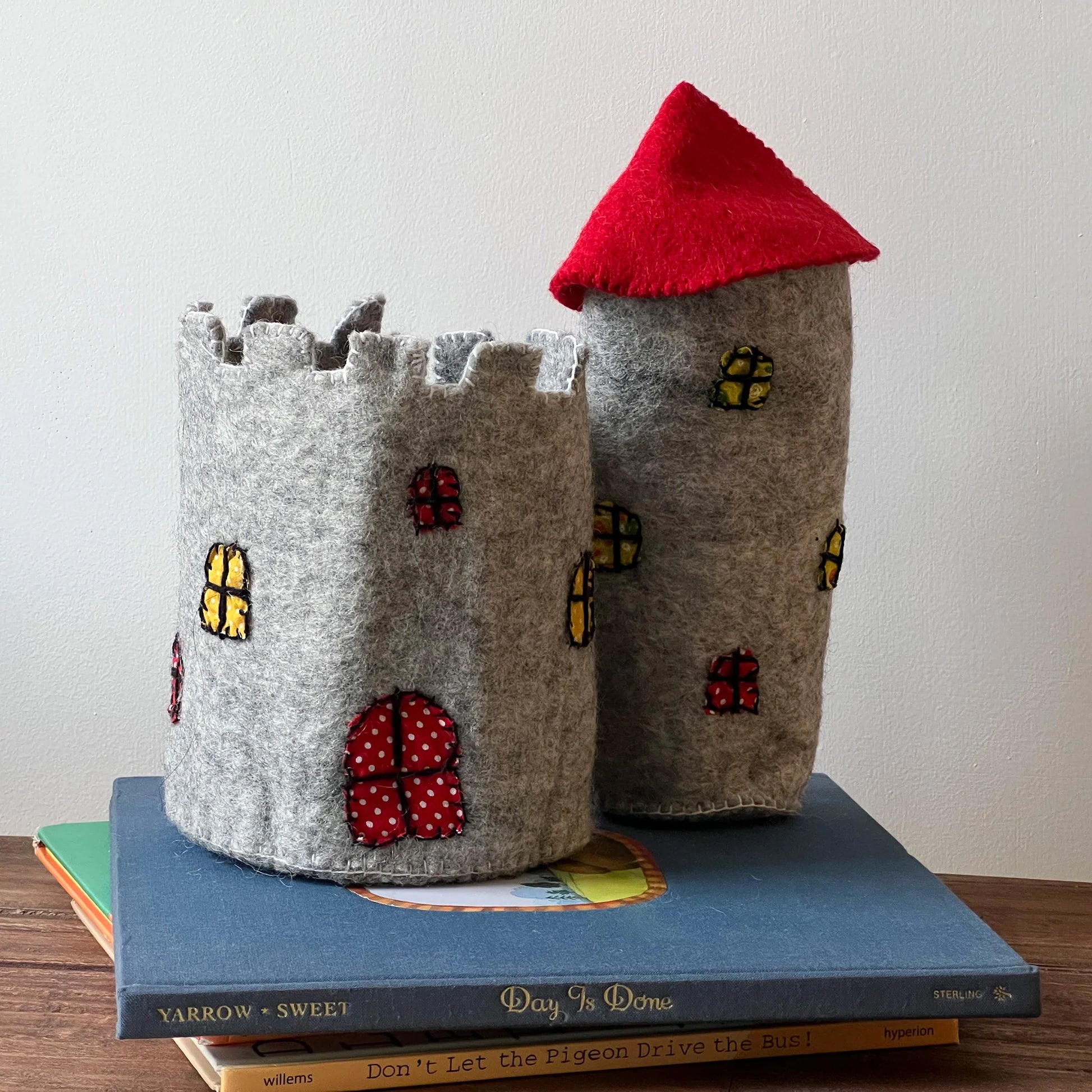 A felt toy castle and tower with a red roof on a stack of books