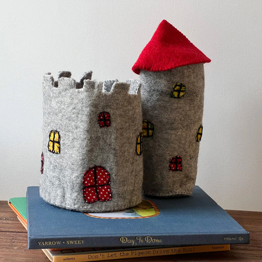 A felt toy castle and tower with a red roof on a stack of books