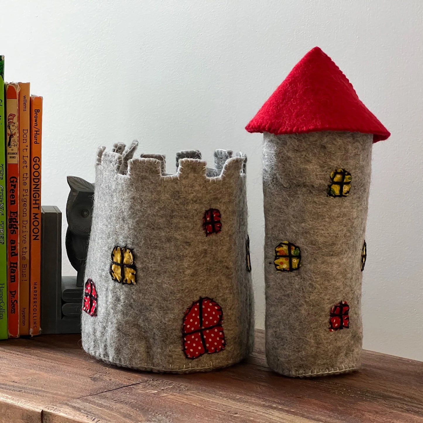 a felt castle and tower toy with a red roof on a shelf.