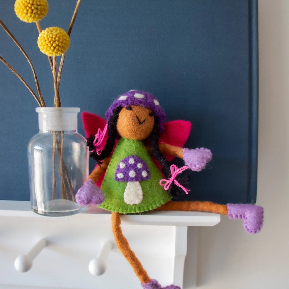 Felt Tooth Fairy doll with brown skin and black hair in a mushroom design and a pocket for a child's lost tooth