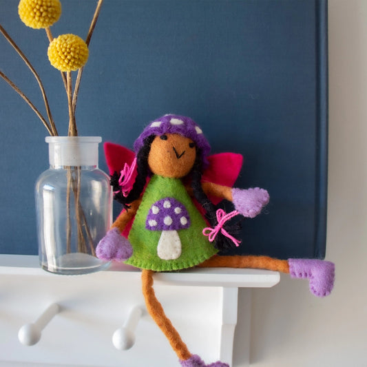 Felt Tooth Fairy doll with brown skin and black hair in a mushroom design and a pocket for a child's lost tooth