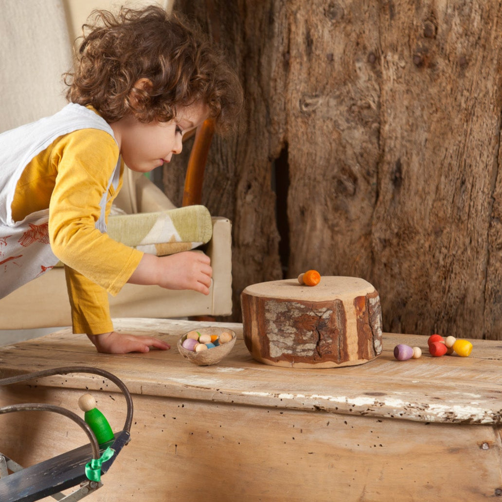 boy playing with grapat light wood baby nins sustainable wooden peg doll toys