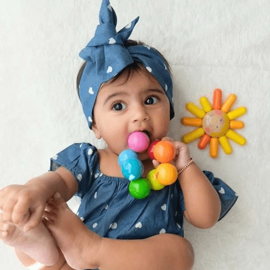 Baby playing with Haba Magica Wooden Rainbow Clutching toy
