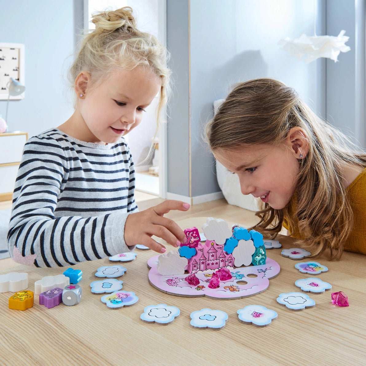 Girls playing Haba Unicorn Glitterluck children's board game, stacking clouds and crystals