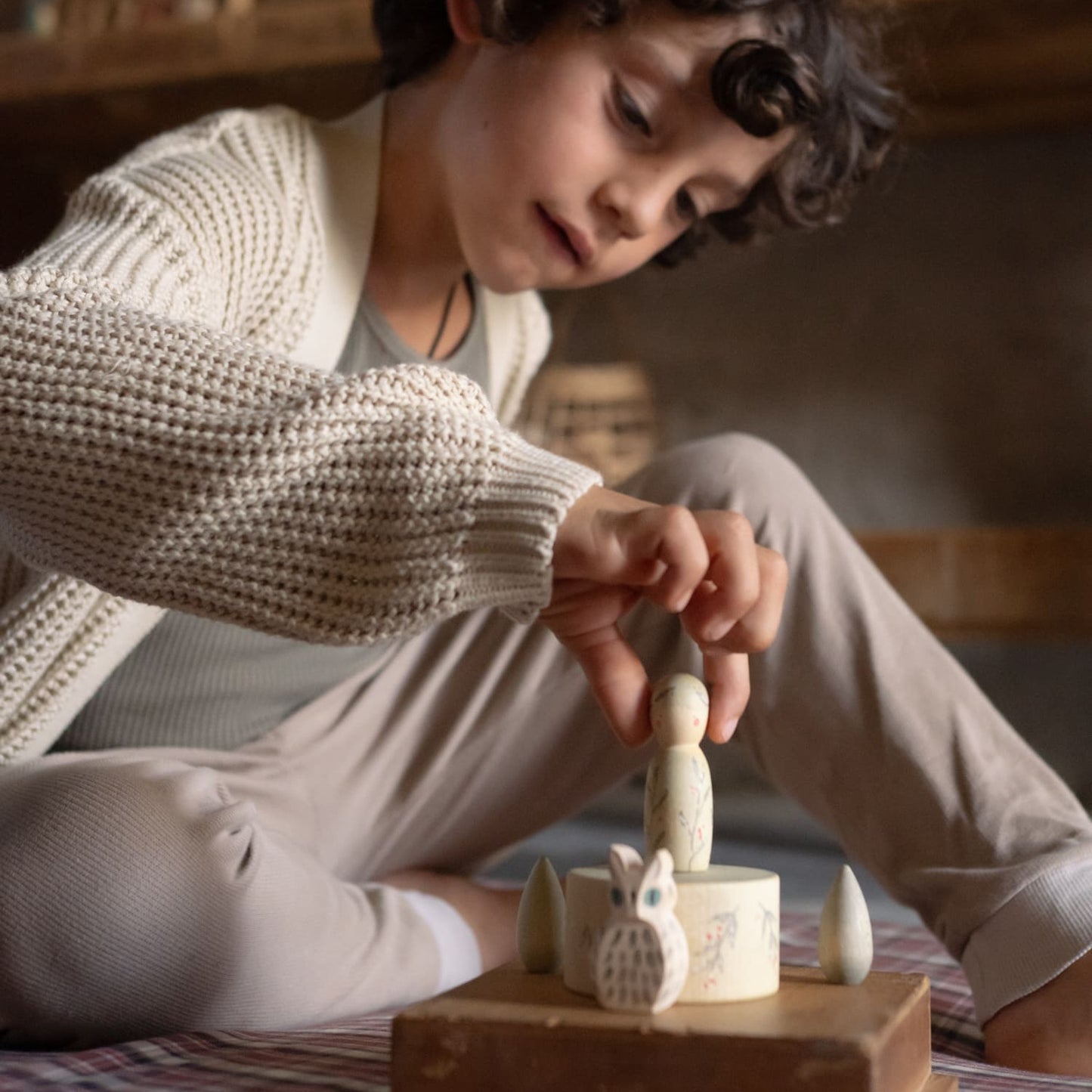 Child playing with Grapat and Ostheimer Limited Edition set of wooden toys including a nin, bowl, owl, and snowflake mandalas