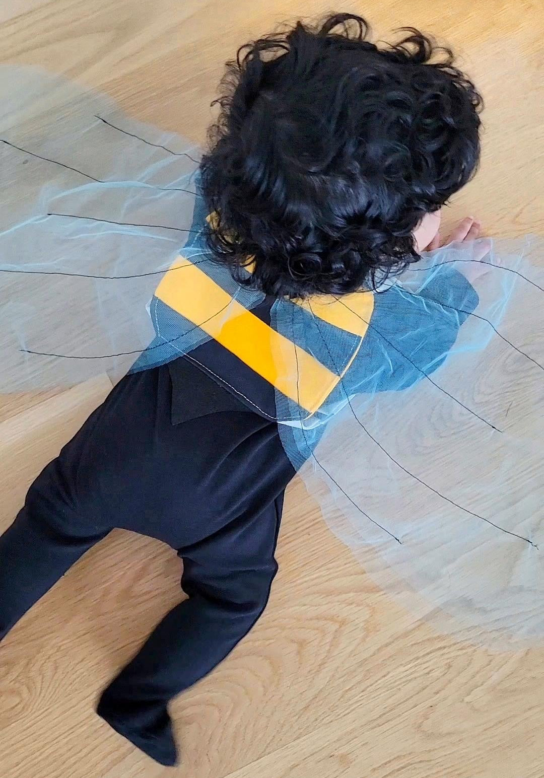 Crawling baby wearing bumble bee costume wings