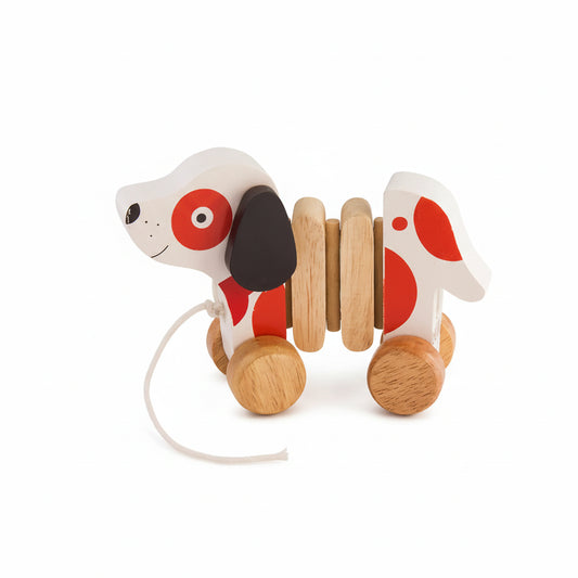 A wooden puppy dog pull toy featuring a white body with red spots, black floppy ears, and natural wood wheels and spine.