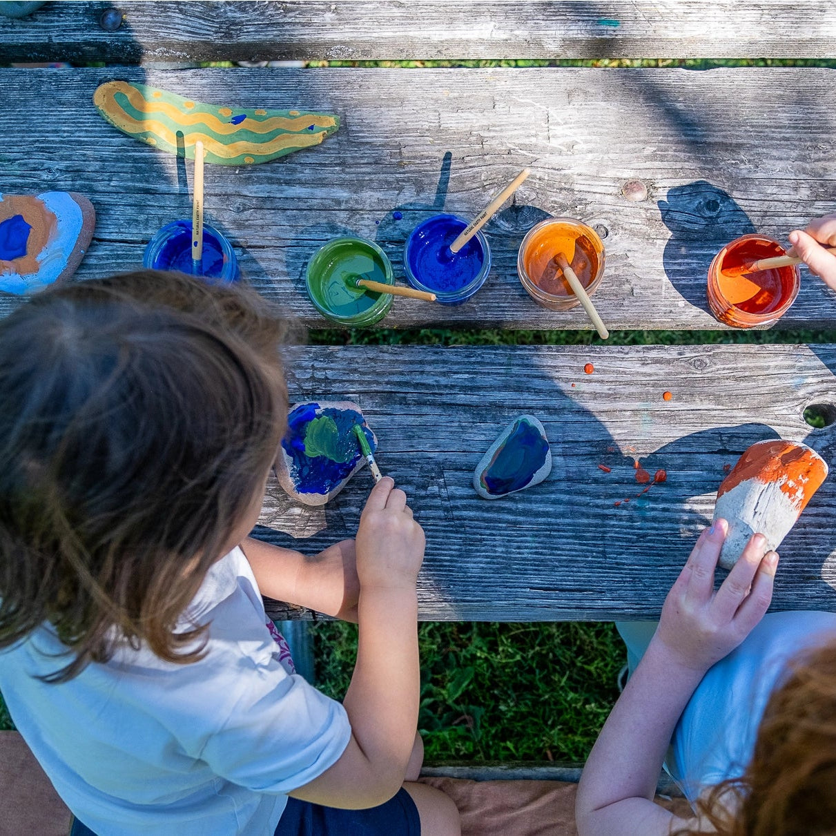 Two children painting rocks with natural earth paint kit