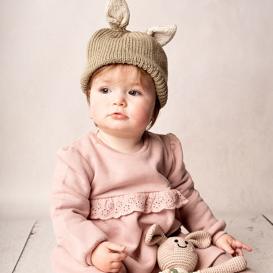 Baby wearing organic hand knit bunny ears hat in brown and beige