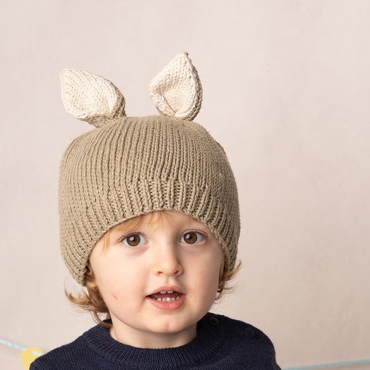 Toddler boy wearing a beige knit bunny ear hat