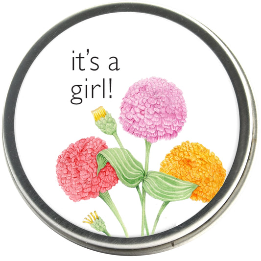 Round tin of Zinnia seeds with 'It's a girl!' and colorful flower illustrated label. 