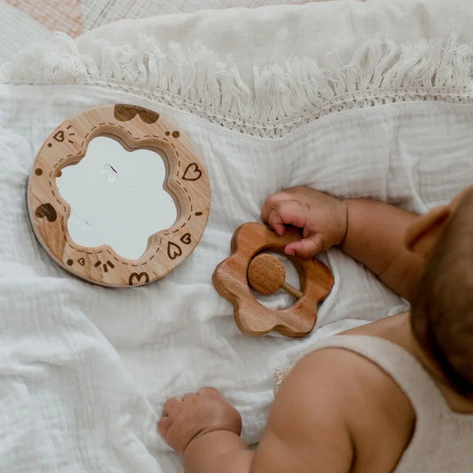 Baby playing with wooden flower rattle and mirror with hearts toys