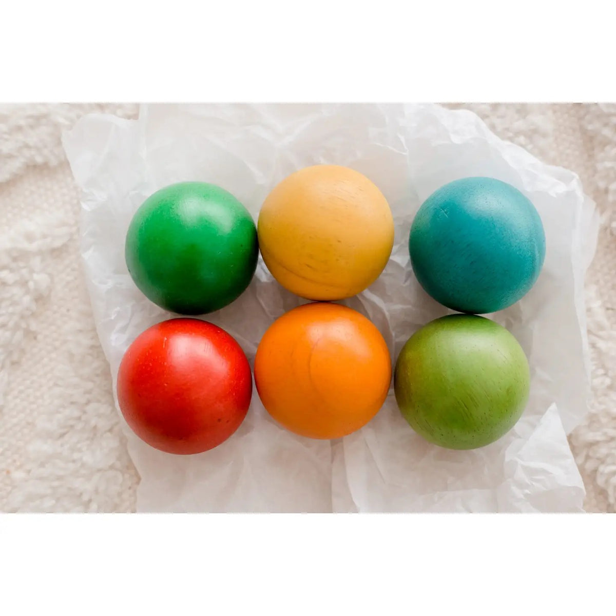 Six colorful wooden toy balls in green, yellow, blue, red, orange, and light green,.