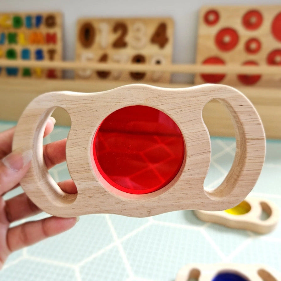 Hand holding a wooden see through red block toy 