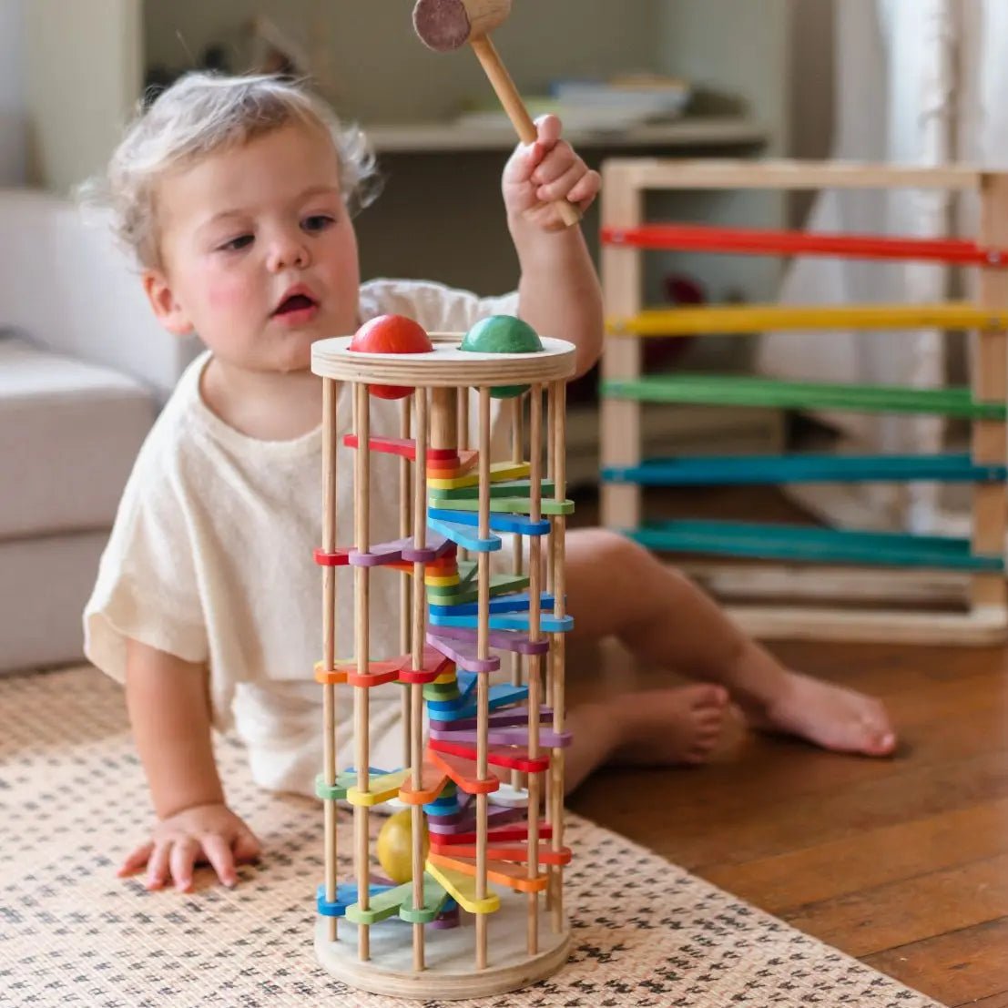 toddler playing with wooden rainbow pound a ball tower toy