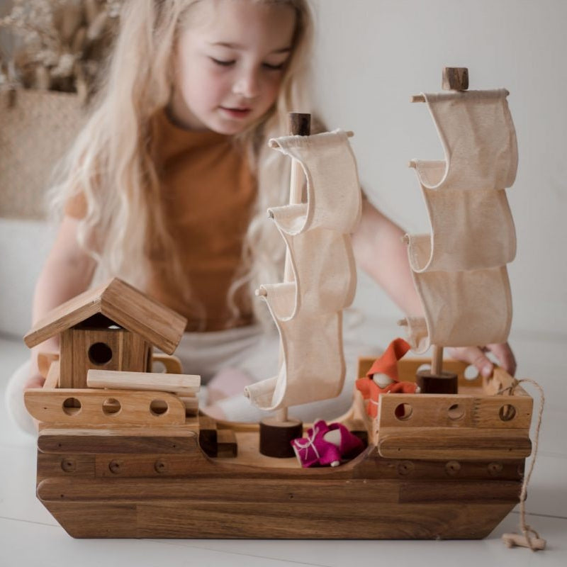 Child playing with Qtoys wooden toy pirate ship and gnome dolls