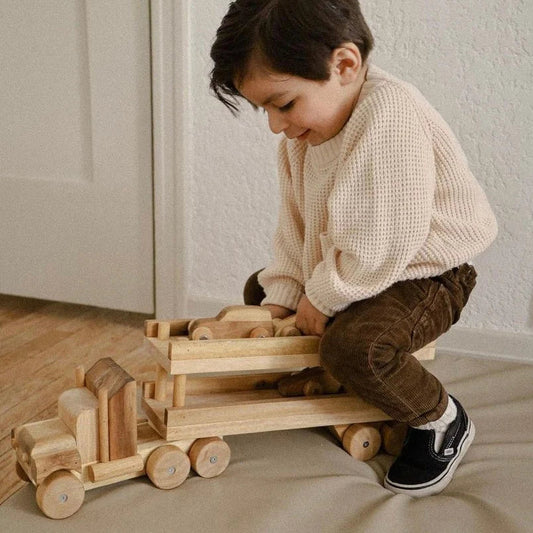 Boy playing with Qtoys all-natural large wooden toy transport truck with cars