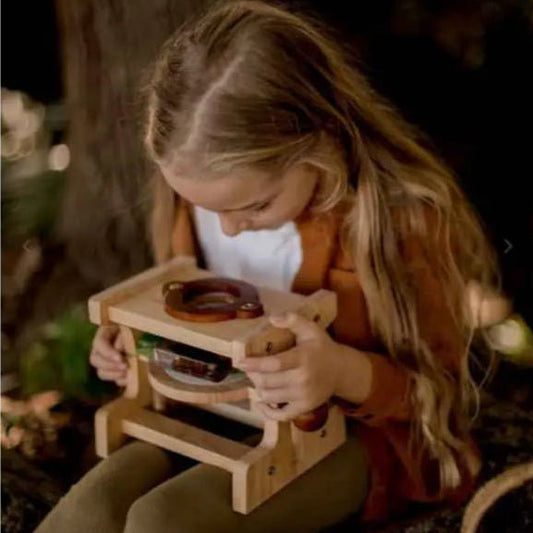 girl looking though wooden microscope toy